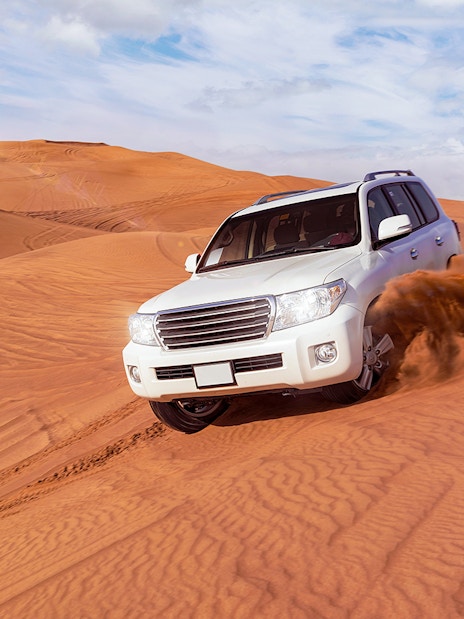 SUVs driving through sand dunes on a desert safari in Dubai.