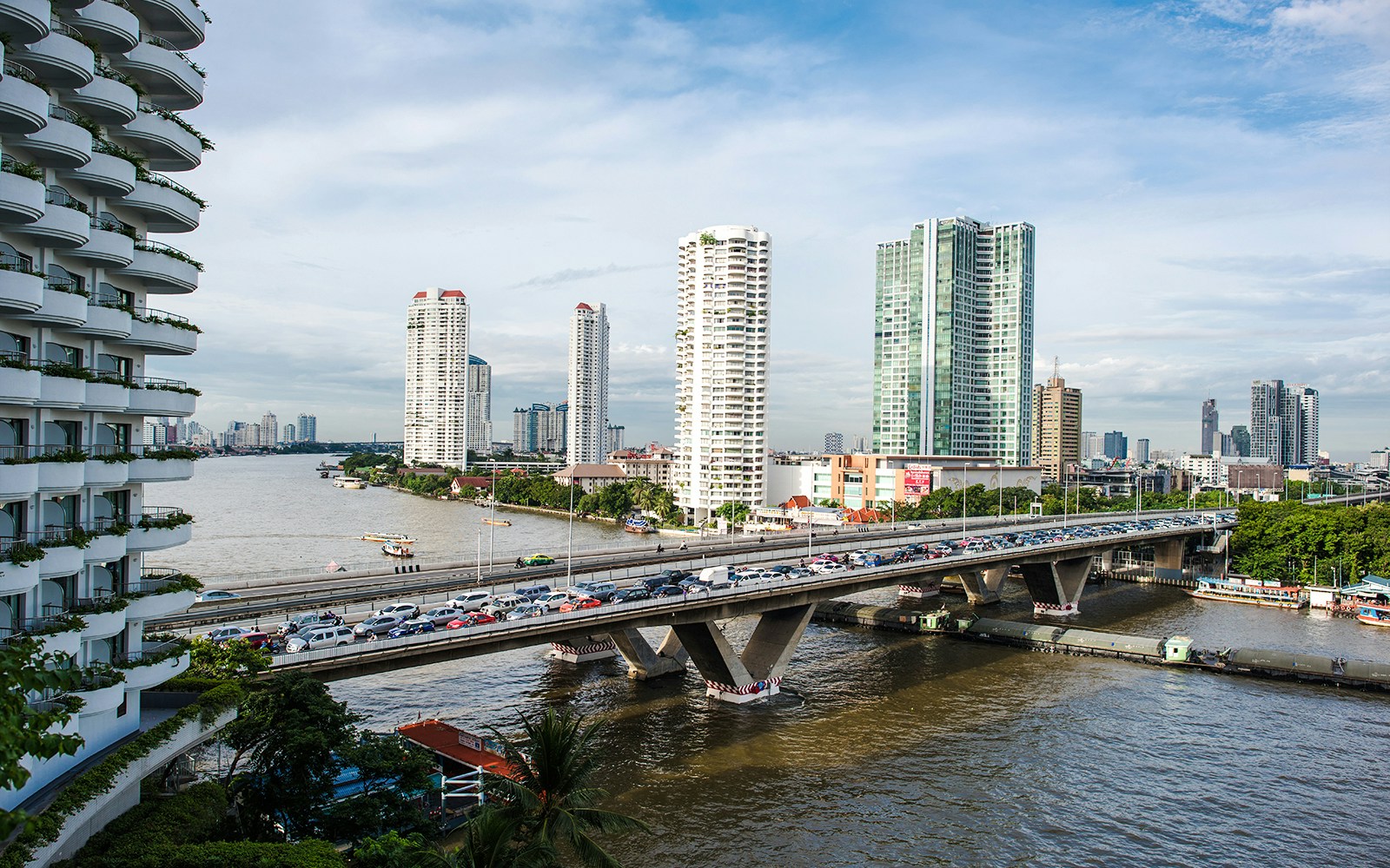 Taksin Bridge over Chao Phraya River with Bangkok skyline in the background.