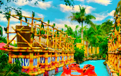 Raft ride at Beto Carrero World with bamboo structures and palm trees, Florianópolis transfer.