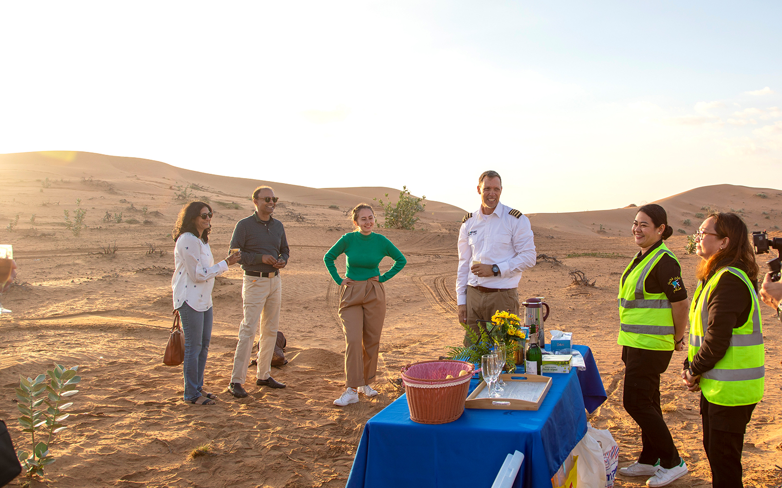 Group enjoying breakfast setup in Ras Al Khaimah desert after hot air balloon ride.