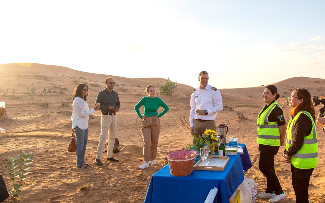 Group enjoying breakfast setup in Ras Al Khaimah desert after hot air balloon ride.