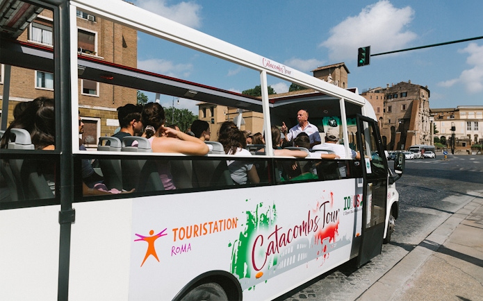 Open-top bus with tourists on a guided tour of Rome's underground catacombs.