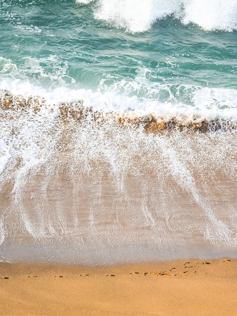 Surfer walking along the beach on the Great Ocean Road, Australia.