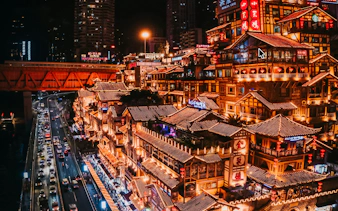 Chongqing night view with illuminated traditional buildings and busy street traffic.