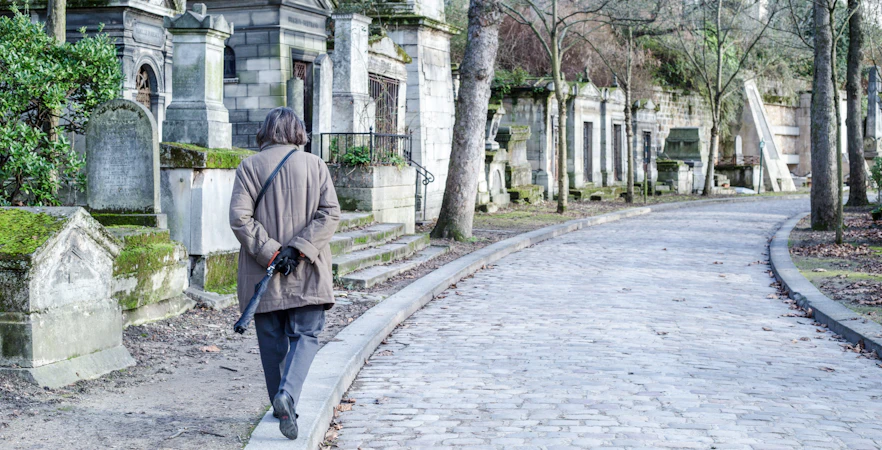Visitor walking along cobblestone path at Père Lachaise Cemetery, Paris.