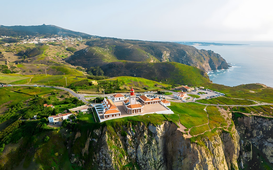 Cape Roca lighthouse on cliff edge overlooking ocean, Cabo da Roca, Portugal.