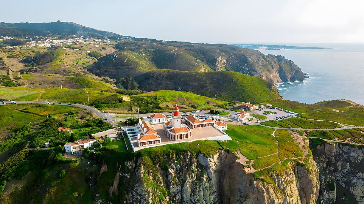 Cape Roca lighthouse on cliff edge overlooking ocean, Cabo da Roca, Portugal.