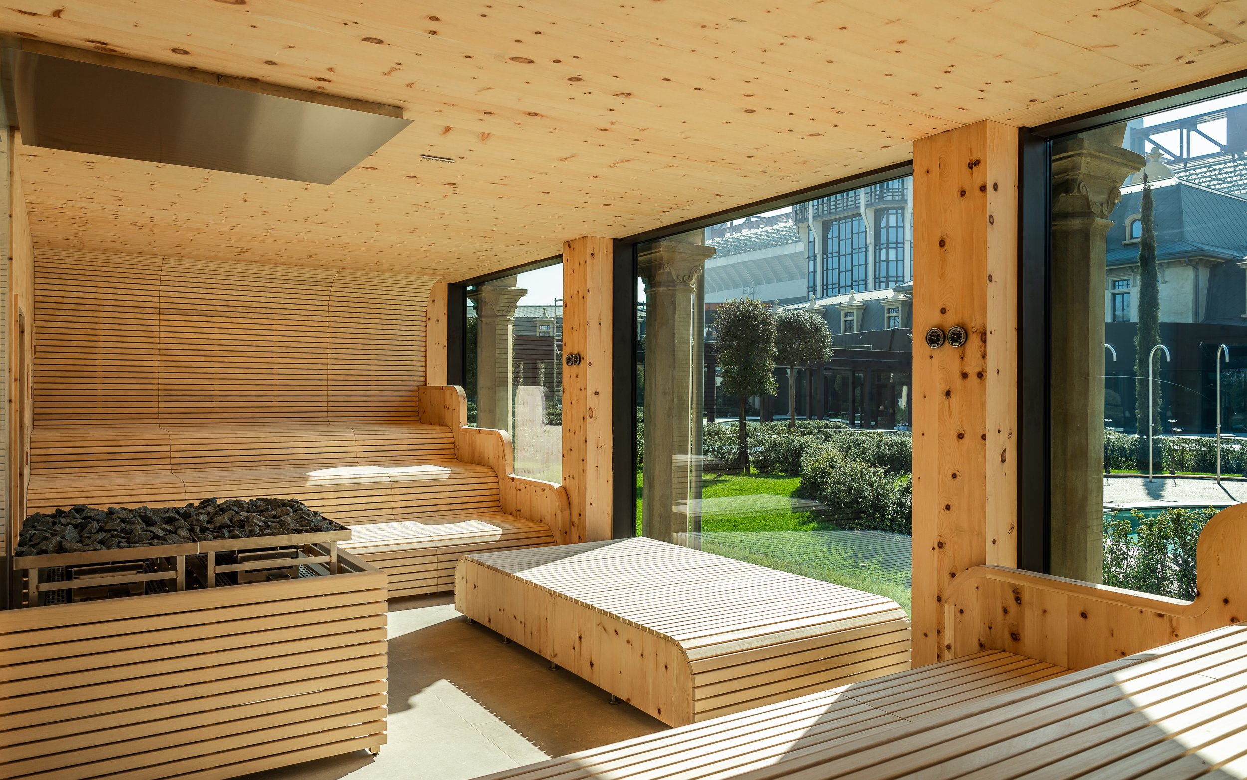Milan spa interior with wooden sauna benches and large windows overlooking a garden.