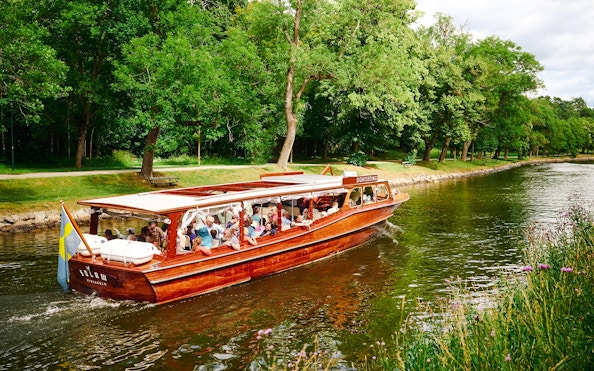 Classic wooden boat cruising through Stockholm Archipelago with passengers enjoying the scenic view.