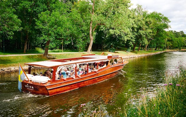 Classic wooden boat cruising through Stockholm Archipelago with passengers enjoying the scenic view.