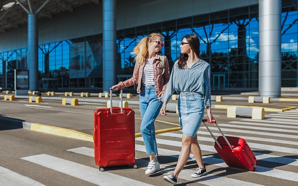 Travelers with luggage outside Singapore Changi Airport for private car transfer.
