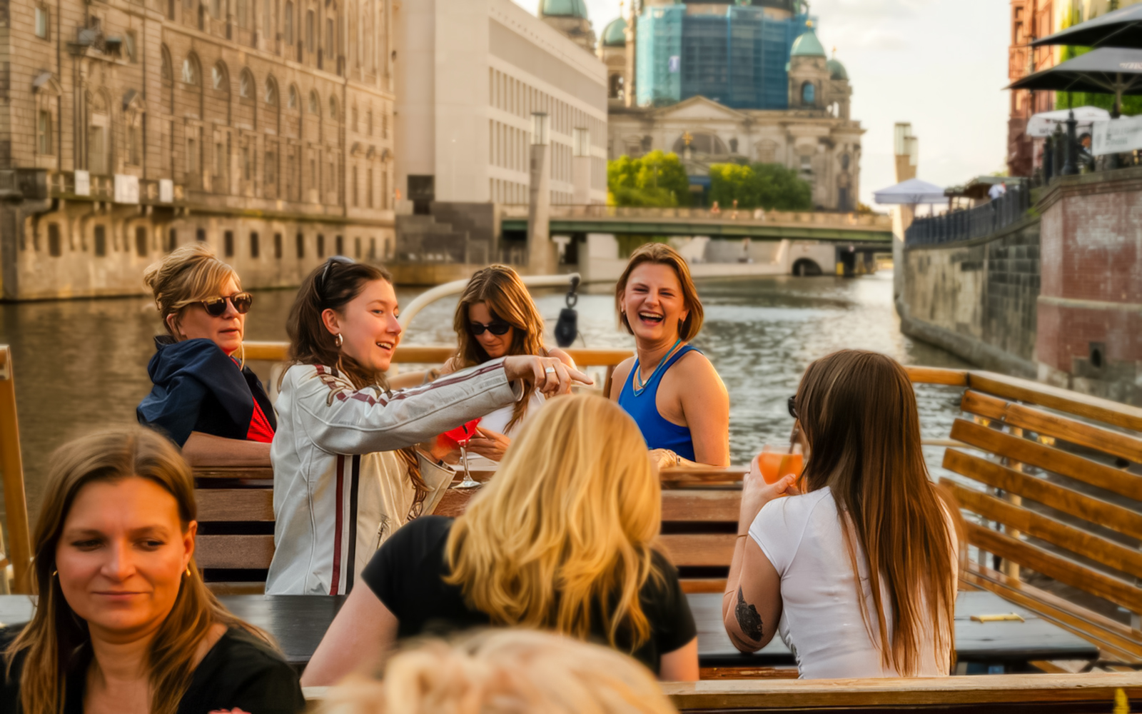 Group enjoying drinks on a Berlin evening cruise with Berlin Cathedral in the background.