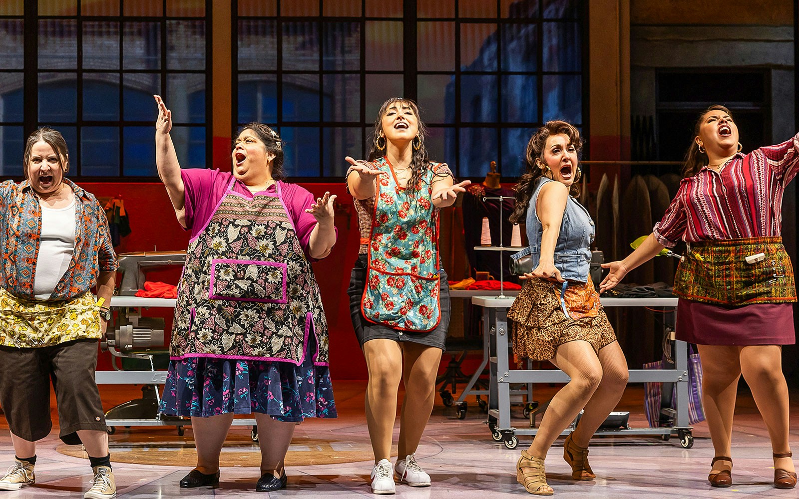 Women performing on stage in "Real Women Have Curves: The Musical" production.