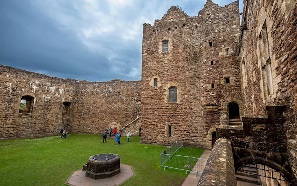Visitors exploring the courtyard of Doune Castle, Scotland.