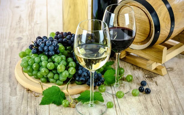 Glasses of red and white wine with grapes and a wine barrel, Erice & Marsala tour.