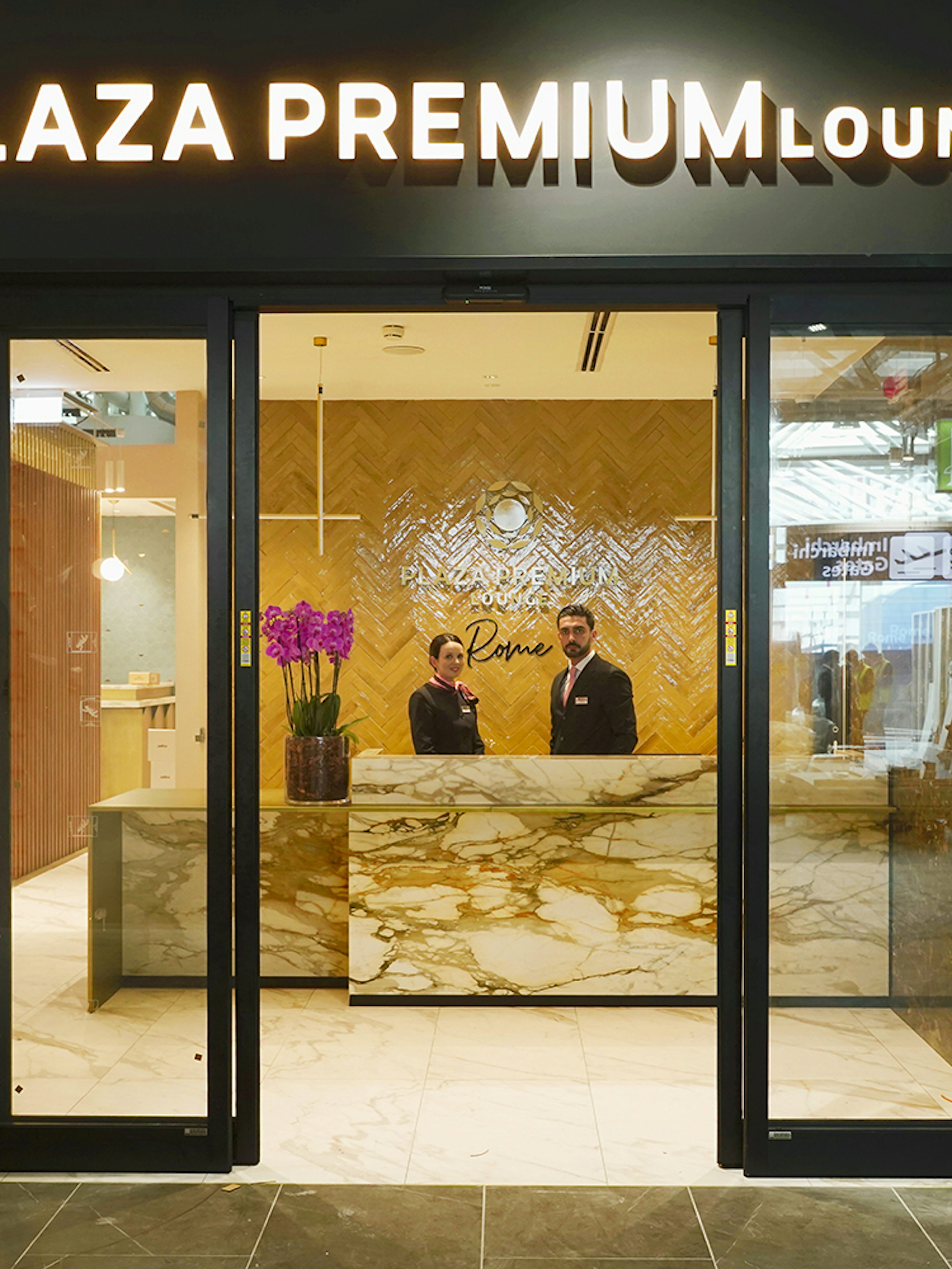 Plaza Premium Lounge entrance at Rome Fiumicino Airport with staff at reception.