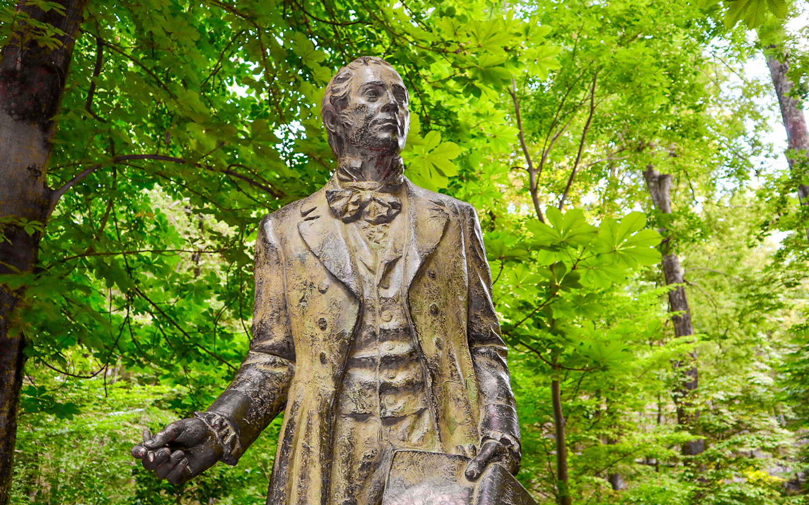 Statue in Alhambra gardens surrounded by lush greenery.