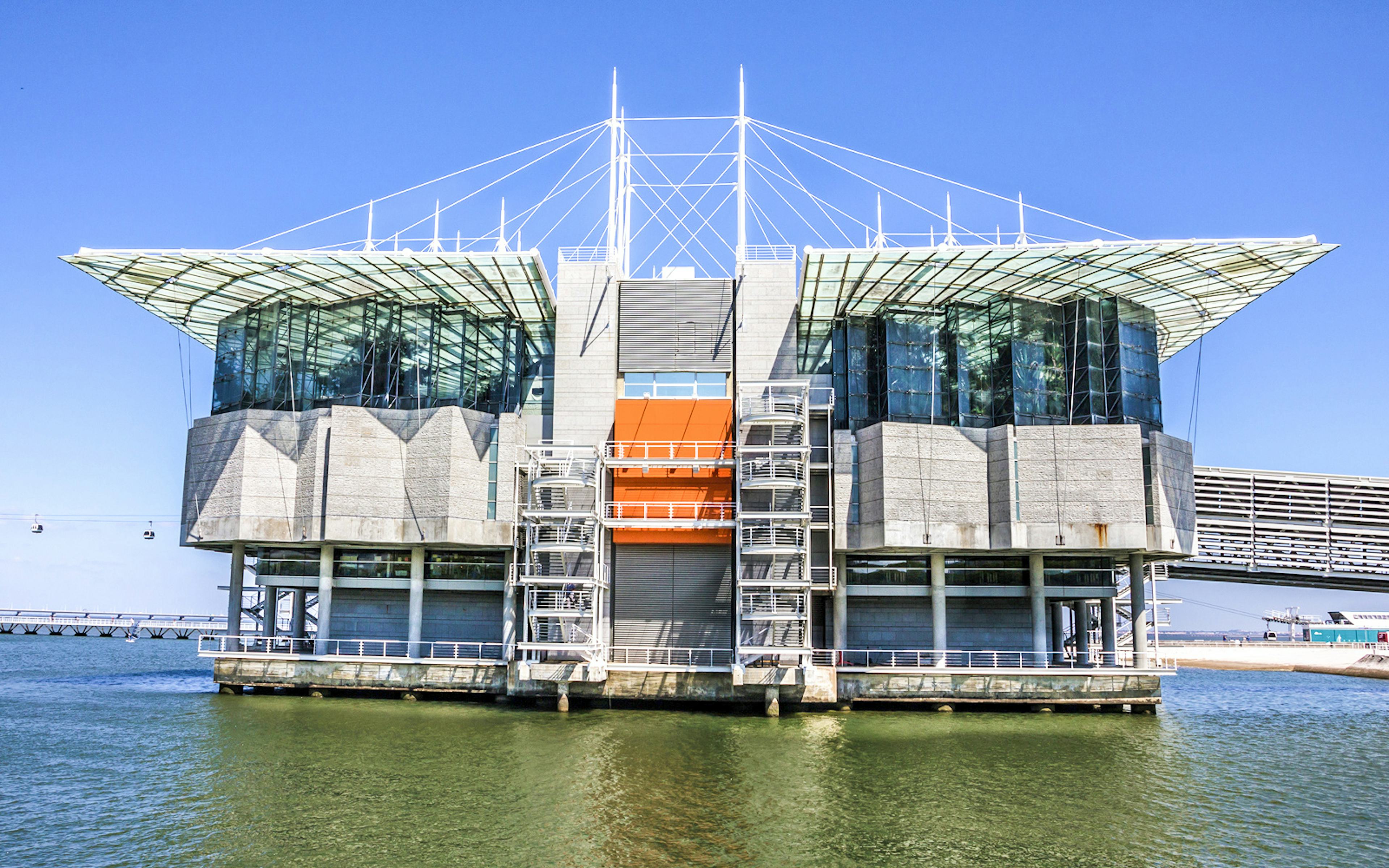 Lisbon Oceanarium exterior with water and cable cars in the background.