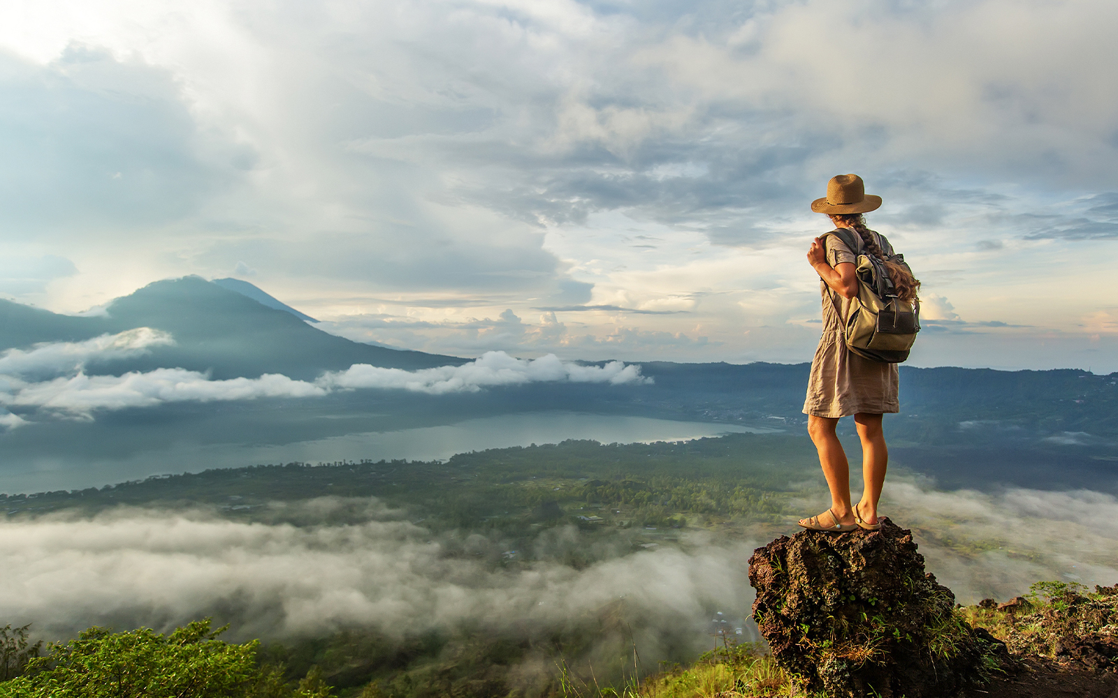 Woman enjoying the sunrise from the top of mountain Batur, Bali