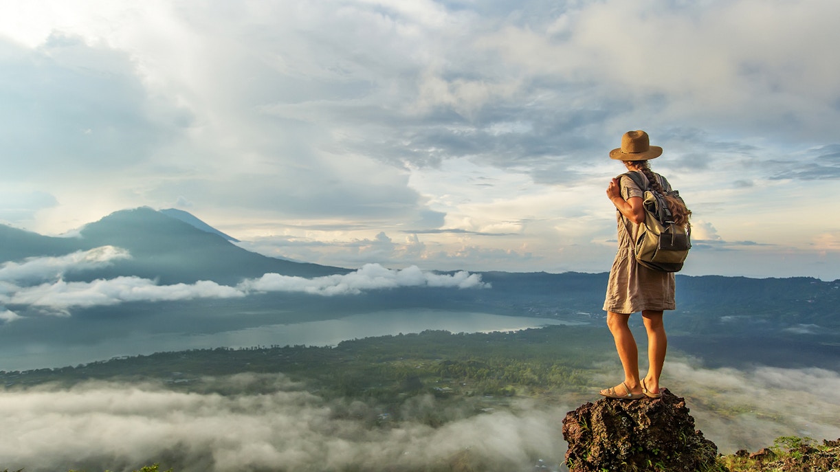Woman enjoying the sunrise from the top of mountain Batur, Bali