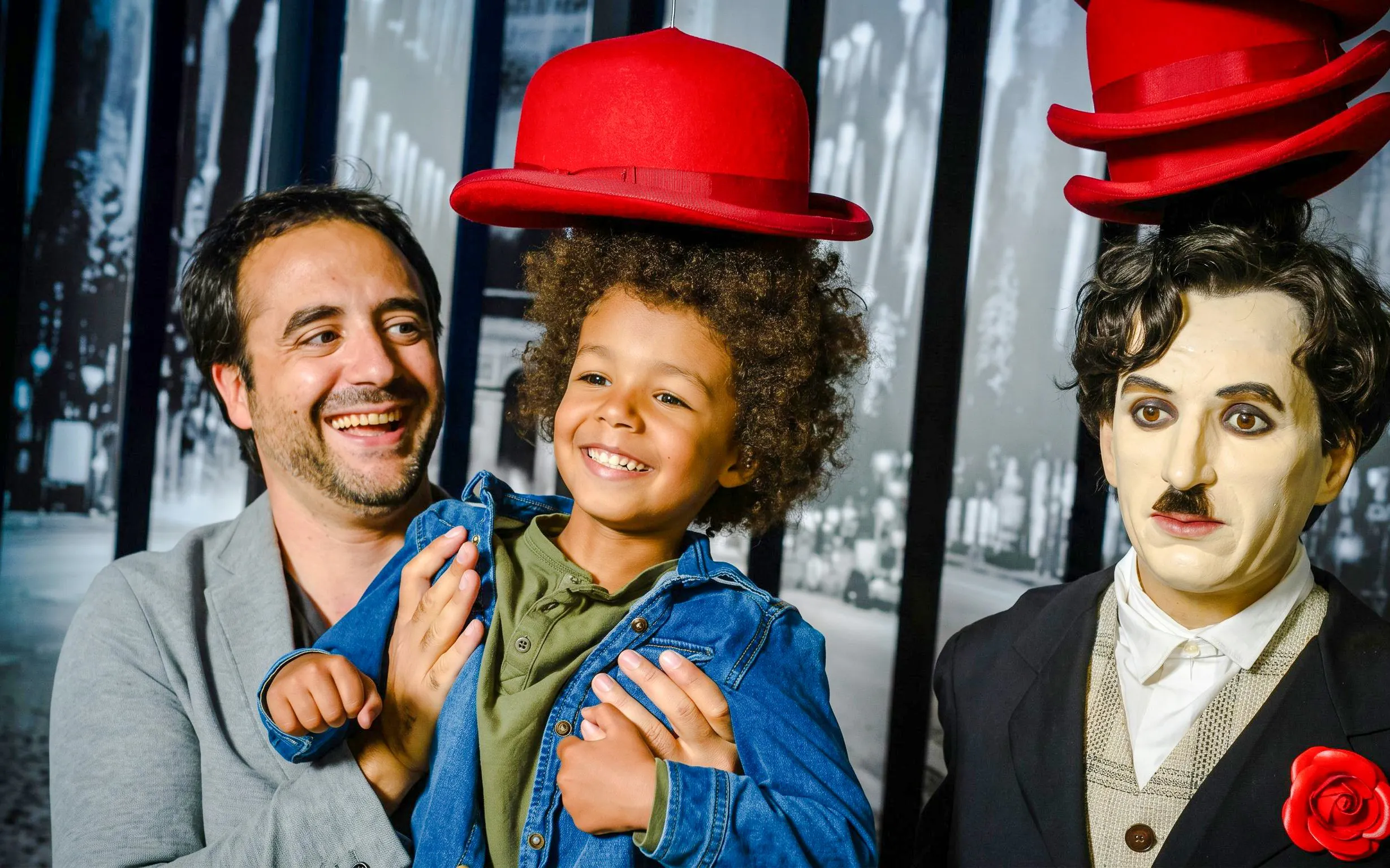 Man and child smiling next to a wax figure at Grévin Wax Museum, Paris.