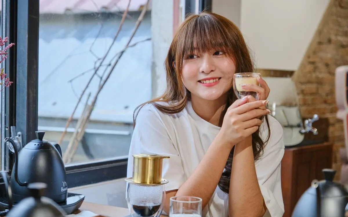 Woman enjoying Vietnamese egg coffee in a cozy café setting.