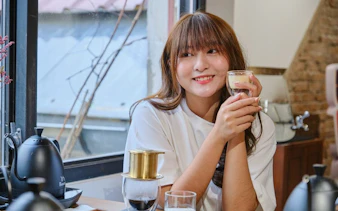 Woman enjoying Vietnamese egg coffee in a cozy café setting.