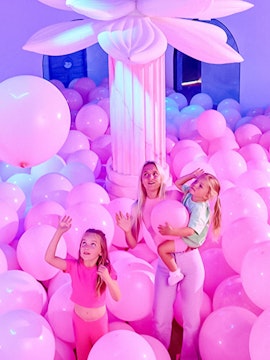 Visitors in a room filled with pink balloons at Bubble Planet An Experience Museum.
