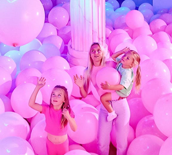 Visitors in a room filled with pink balloons at Bubble Planet An Experience Museum.