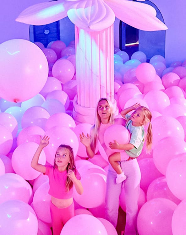Visitors in a room filled with pink balloons at Bubble Planet An Experience Museum.