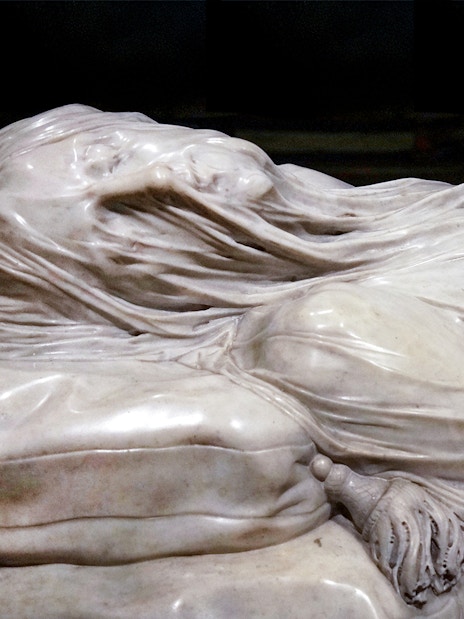 Close-up of the Veiled Christ statue in Naples, Italy, showcasing intricate marble drapery.