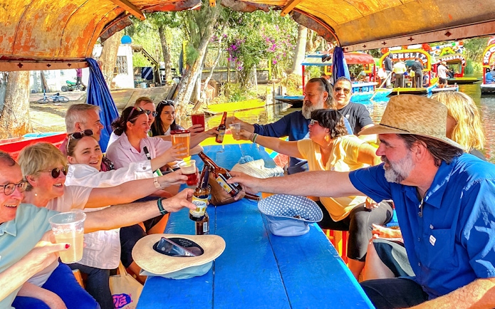 Group enjoying drinks on a colorful boat during Xochimilco tour in Mexico City.