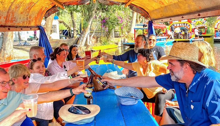 Colorful trajinera boats on Xochimilco canal, Mexico City, with tourists enjoying a guided tour.
