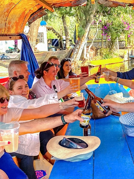 Group enjoying drinks on a colorful boat during Xochimilco tour in Mexico City.