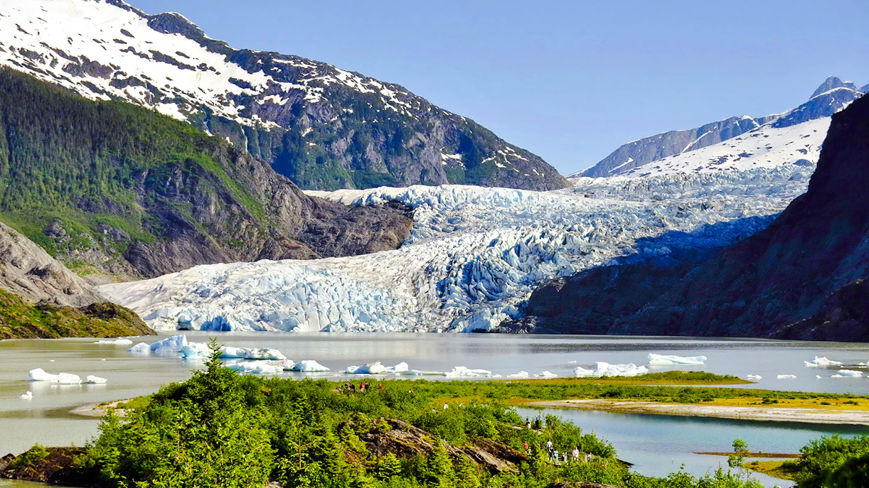 Mendenhall Glacier in Alaska with surrounding mountains and icy lake.