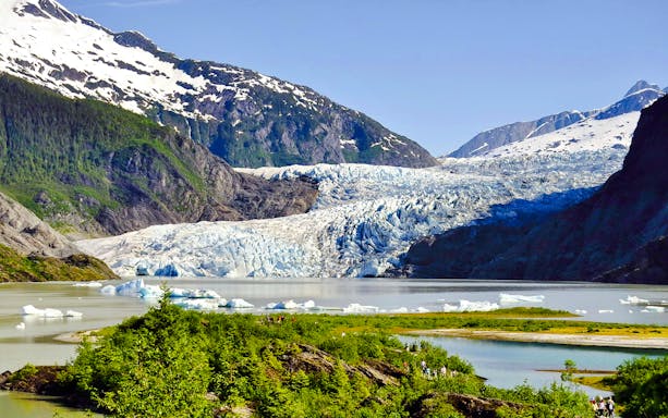 Mendenhall Glacier in Alaska with surrounding mountains and icy lake.