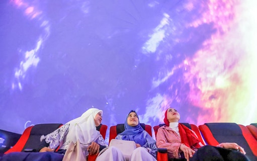 Tourists watching a 360-degree projection show in a theater.
