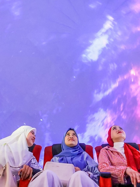 Tourists watching a 360-degree projection show in a theater.