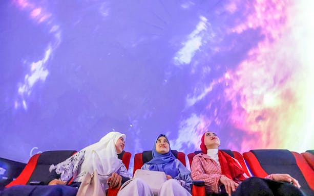 Tourists watching a 360-degree projection show in a theater.