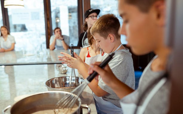 Children learning to make pizza dough in a cooking class in Palermo.