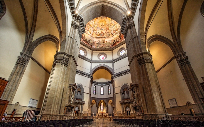 Interior of Cathedral of Santa Maria del Fiore, Florence, showcasing ornate dome frescoes and arches.