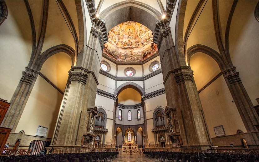 Interior of Cathedral of Santa Maria del Fiore, Florence, showcasing ornate dome frescoes and arches.