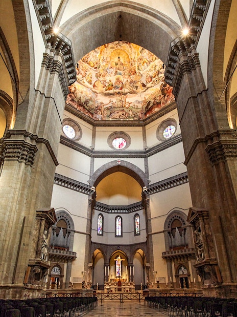 Interior of Cathedral of Santa Maria del Fiore, Florence, showcasing ornate dome frescoes and arches.