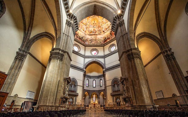 Interior of Cathedral of Santa Maria del Fiore, Florence, showcasing ornate dome frescoes and arches.