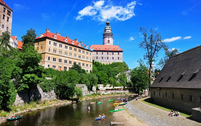 Cesky Krumlov Castle exterior with kayakers on the Vltava River.