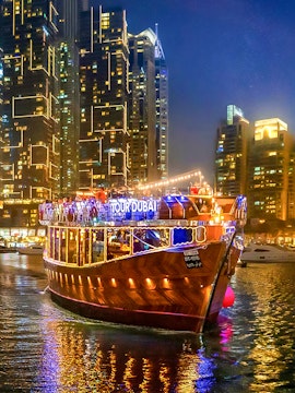 Dubai Marina evening cruise with illuminated dhow boat and city skyline.