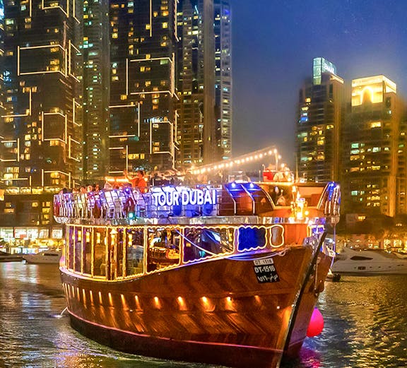 Dubai Marina evening cruise with illuminated dhow boat and city skyline.