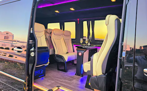 Luxury van interior for private transfer in Santorini with champagne glasses on table.