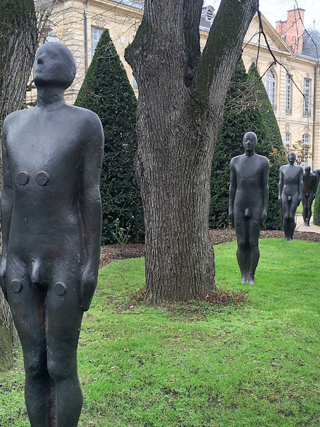 Sculptures in the garden of the Rodin Museum, Paris, with historic building in background.