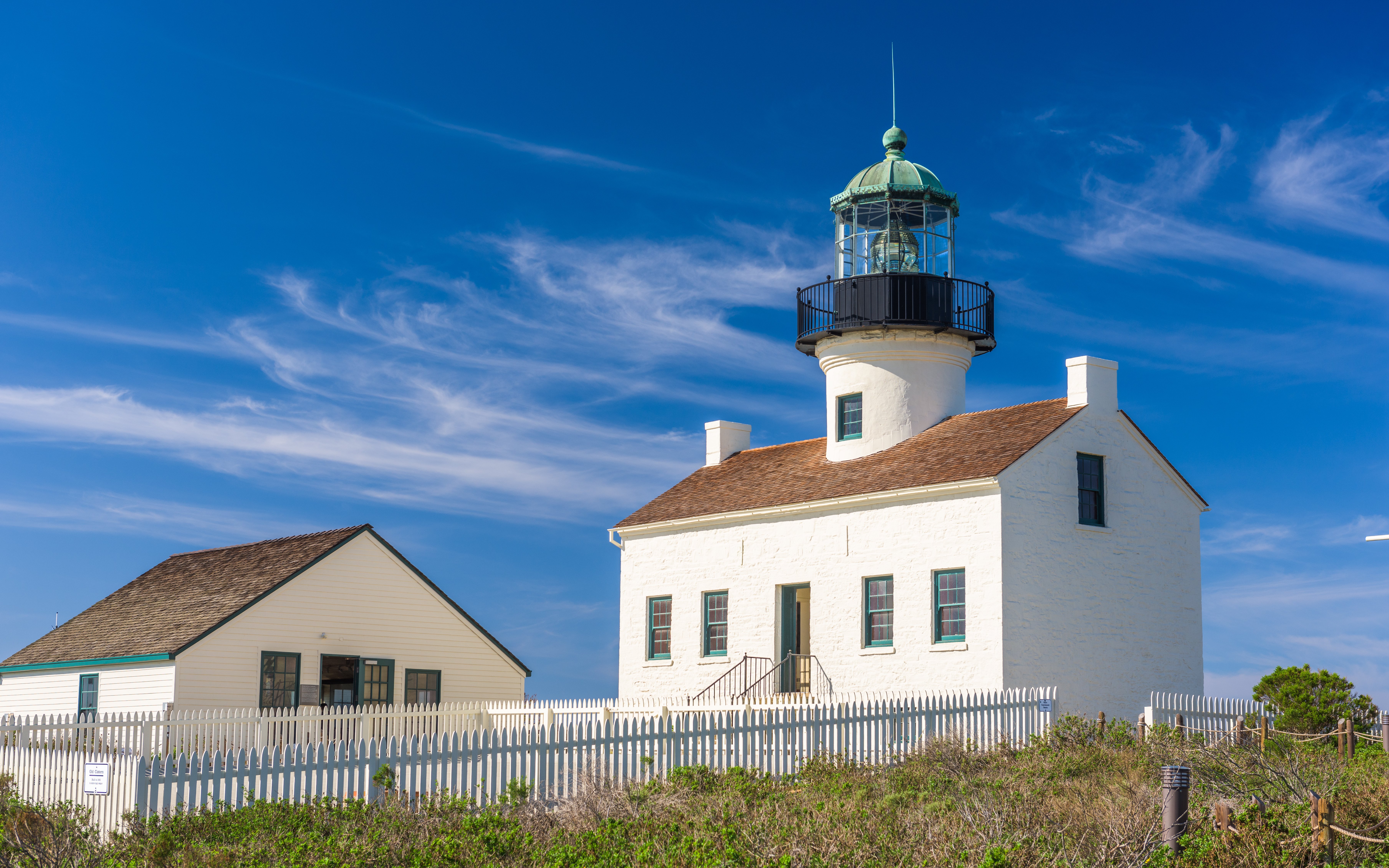Point Loma Lighthouse with white picket fence under clear blue sky in San Diego.